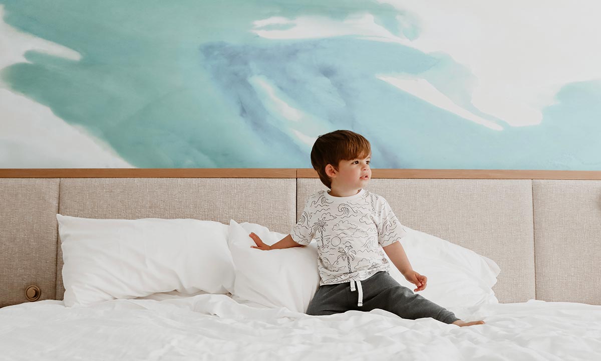 Small child playing on guest room bed. 