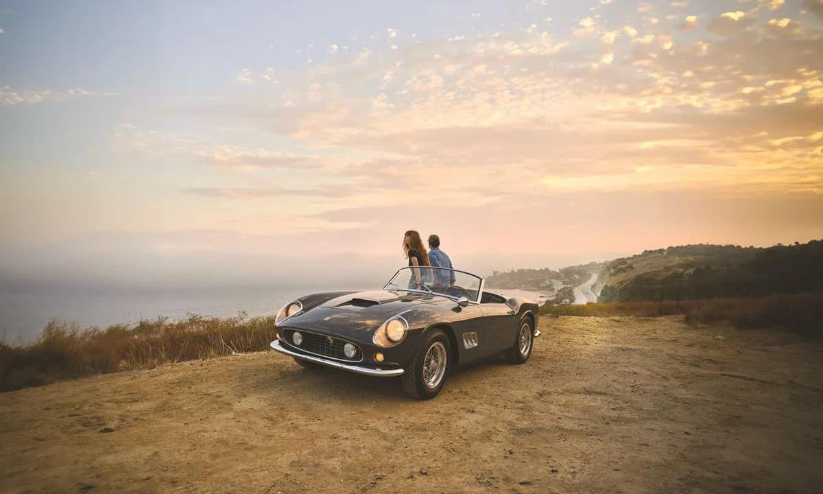 Couple in classic car at the beach at sunset