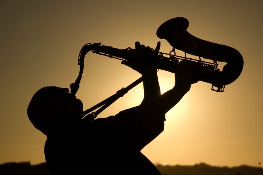 man playing saxophone at sunset