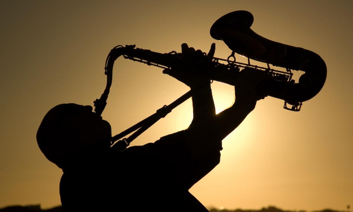 man playing horn at sunset